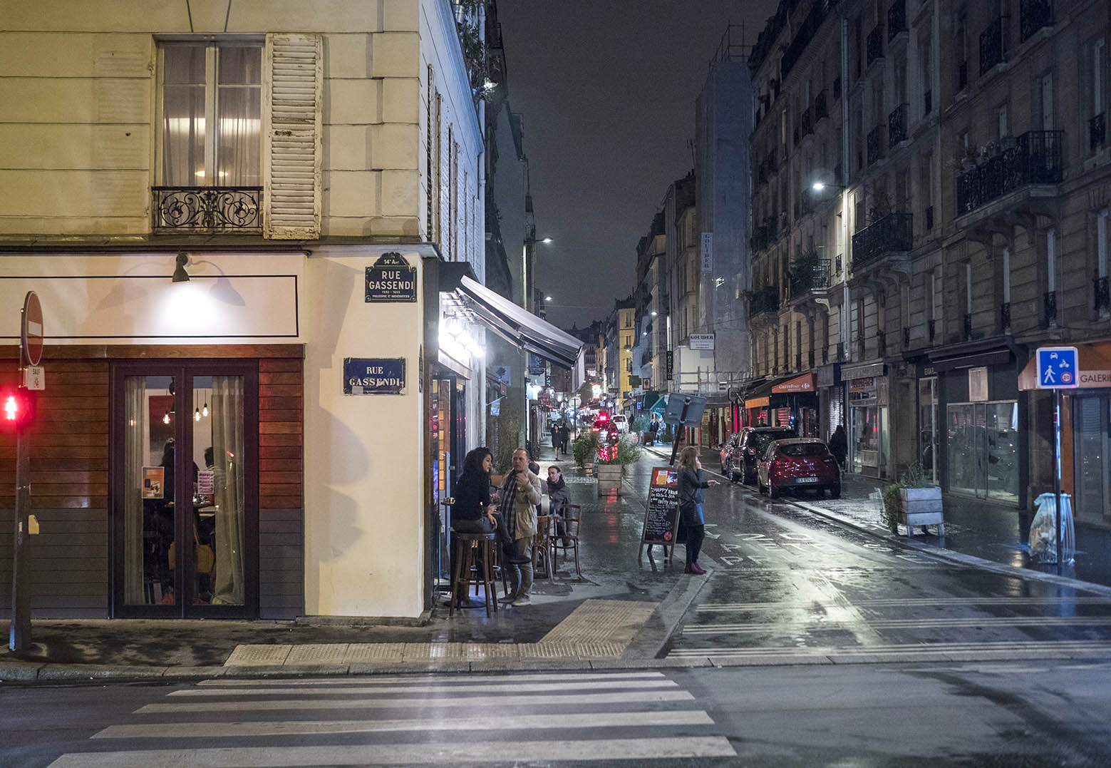 Midnatt på rue Daguerre i Paris. Det regnar och är kyligt, med franska mått. Endast rökarna sitter kvar på uteserveringen. Olympus OM-D E-M1 II med zuiko 50 mm 1,2. 1/40 sec och bländare 1,8